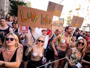 Menschen nehmen im Jahr 2024 an der Technoparade „Zug der Liebe“ - Demonstration für Toleranz, Vielfalt und Miteinander mit einem Schild mit der Aufschrift „love wins“ teil.