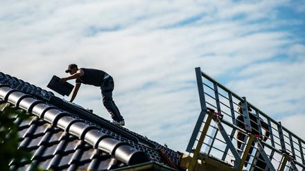 Ein Arbeiter bereitet das Dach für die anschließende Montage von Solarpanels vor (Symbolbild).