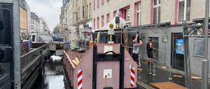 An einem Haus mit einem beschädigten Dach wird ein Schutztunnel für Fußgänger aufgestellt. 