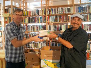 Jordan Wegberg (rechts) übergibt eine Bücherspende an den Leiter der Berliner "Vita-Bücherbörse", Lars Friedrich.