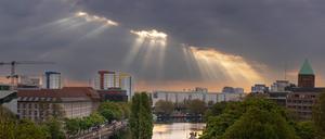 Sonnenstrahlen durchbrechen morgens die Wolken über Berlin. 