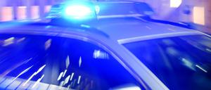 Ein Streifenwagen der Polizei steht mit eingeschaltetem Blaulicht auf der Straße.