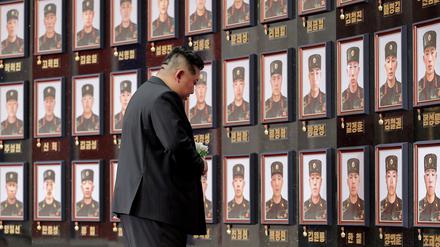 Der nordkoreanische Staatschef Kim Jong Un steht vor einer Portraitwand gefallener Soldaten. 