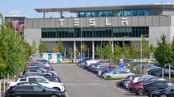 Autos parken vor dem Werk der Tesla-Gigafactory Berlin-Brandenburg  in Grünheide.