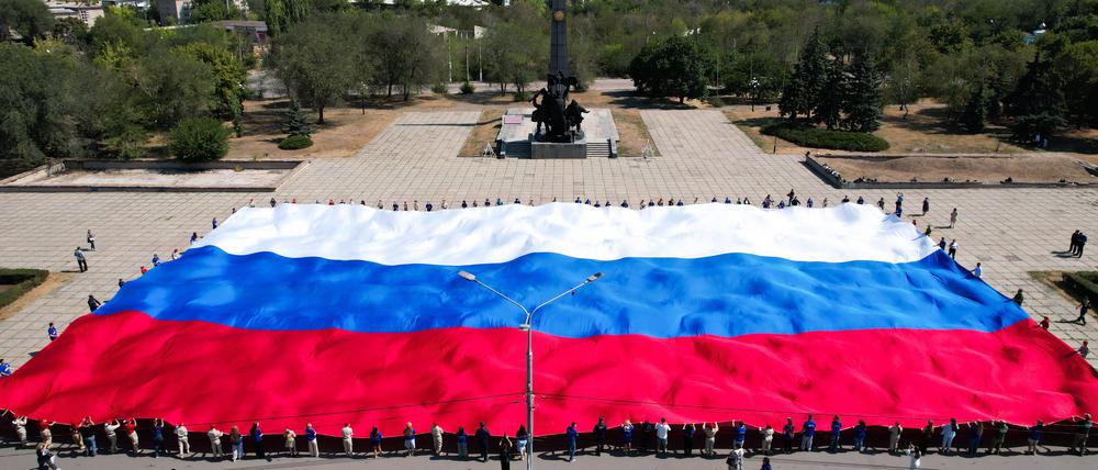 Eine russische Flagge wird vor dem Denkmal für die Befreier in der von Russland annektierten Stadt Luhansk ausgebreitet.