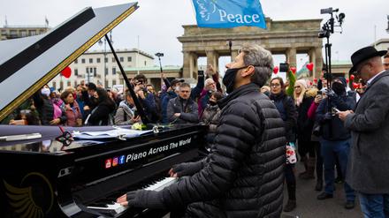 Der Pianist Arne Schmitt spielt mit seinem Klavier vor dem Brandenburger Tor.