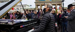 Der Pianist Arne Schmitt spielt mit seinem Klavier vor dem Brandenburger Tor.