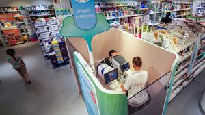 Eine Verkäuferin führt in einer DM-Filiale in Düsseldorf ein Augenscreening bei einem Kunden durch.