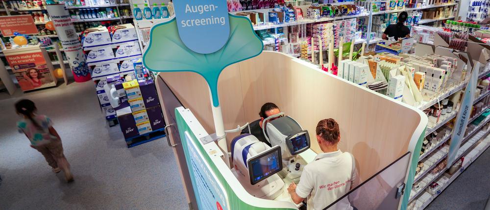 Eine Verkäuferin führt in einer DM-Filiale in Düsseldorf ein Augenscreening bei einem Kunden durch.