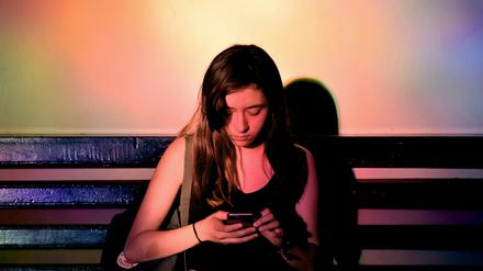Eine junge Frau scrollt durch ihr Handy.