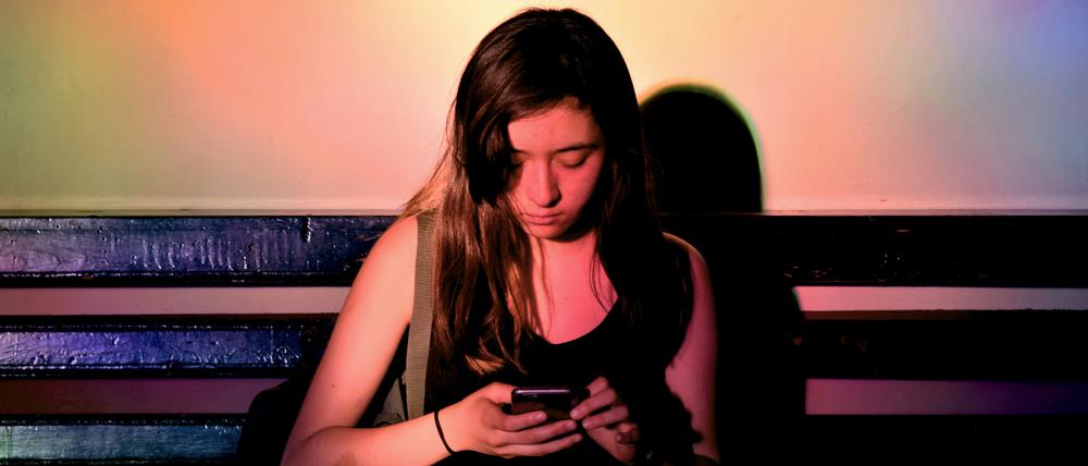 Eine junge Frau scrollt durch ihr Handy.