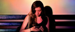 Eine junge Frau scrollt durch ihr Handy.