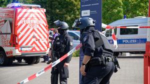 Polizisten stehen an einem Berufskolleg in Essen an einer Absperrung.