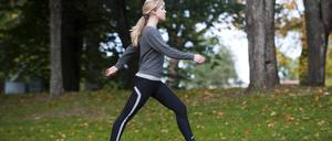 Eine Frau geht schnellen Schrittes durch einen Park.