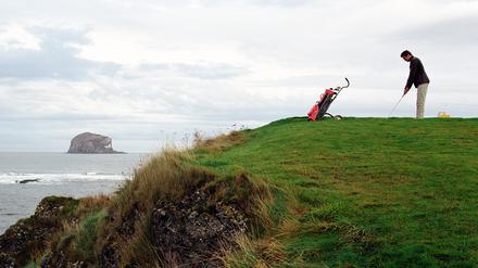 Scotland, Aberlady Bay, man playing golf by sea