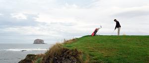Scotland, Aberlady Bay, man playing golf by sea