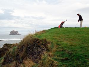 Scotland, Aberlady Bay, man playing golf by sea