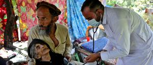 Ein Arzt versorgt Rad Bibi, eine verletzte afghanische Frau, die angibt, 110 Jahre alt zu sein, vor ihrem beschädigten Haus nach dem schweren Erdbeben in der Provinz Kunar in Afghanistan.
