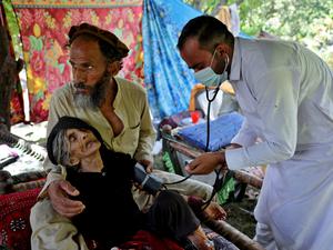 Ein Arzt versorgt Rad Bibi, eine verletzte afghanische Frau, die angibt, 110 Jahre alt zu sein, vor ihrem beschädigten Haus nach dem schweren Erdbeben in der Provinz Kunar in Afghanistan.