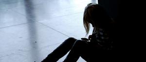 Ein kleines Mädchen sitzt mit gesenktem Kopf allein auf dem Fußboden. (Symbolbild)