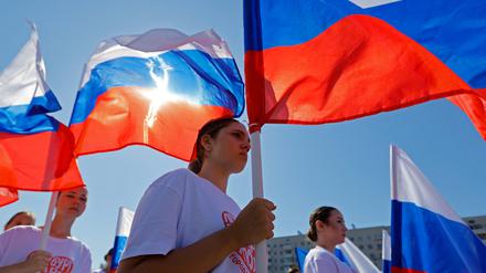 People hold Russian flags during celebrations of National Flag Day in Mariupol, a Russian-controlled city of Ukraine, August 22, 2025. REUTERS/Alexander Ermochenko