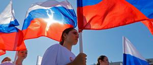 Jugendliche in Mariupol tragen russische Flaggen während der Feierlichkeiten zum russischen Nationalflaggentag.