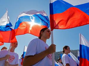 People hold Russian flags during celebrations of National Flag Day in Mariupol, a Russian-controlled city of Ukraine, August 22, 2025. REUTERS/Alexander Ermochenko