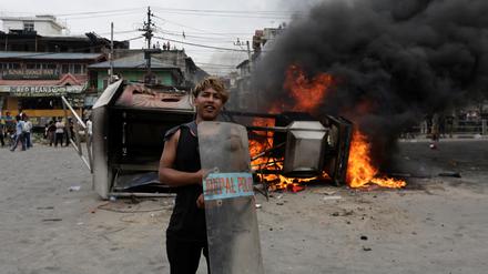 Ein Demonstrant in Nepal vor einem brennenden Auto.