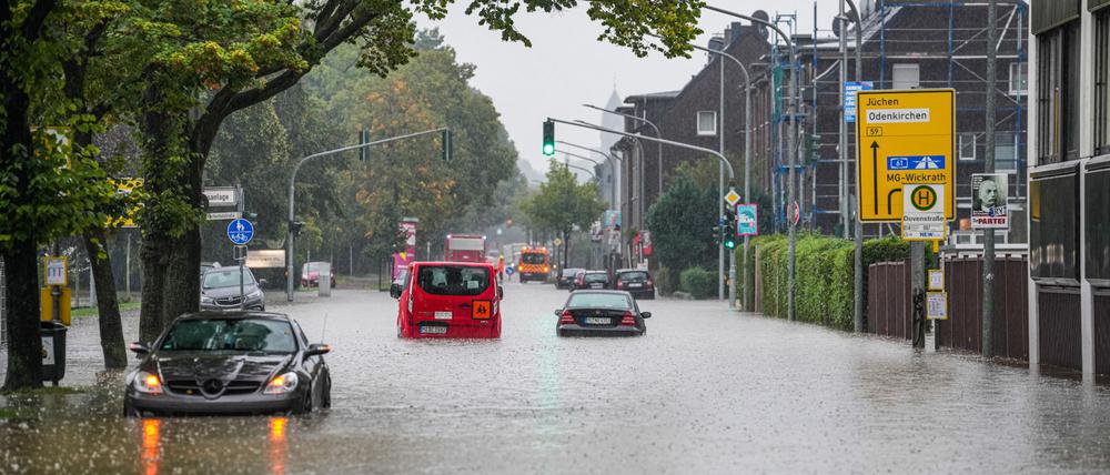 Autos fahren bei starkem Regen durch eine überflutete Straße. 