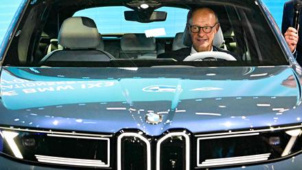Friedrich Merz nimmt beim  Rundgang über die IAA in einem BMW IX3 Platz.