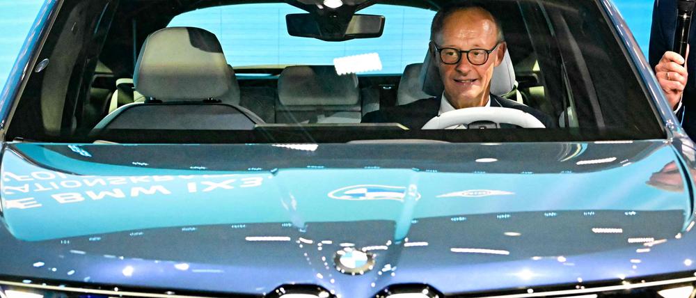 Friedrich Merz nimmt beim  Rundgang über die IAA in einem BMW IX3 Platz.
