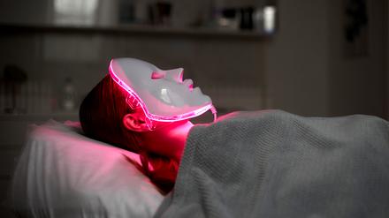 Eine Frau lässt sich mit einer LED-Maske mit rotem Licht behandeln. (Symbolbild)