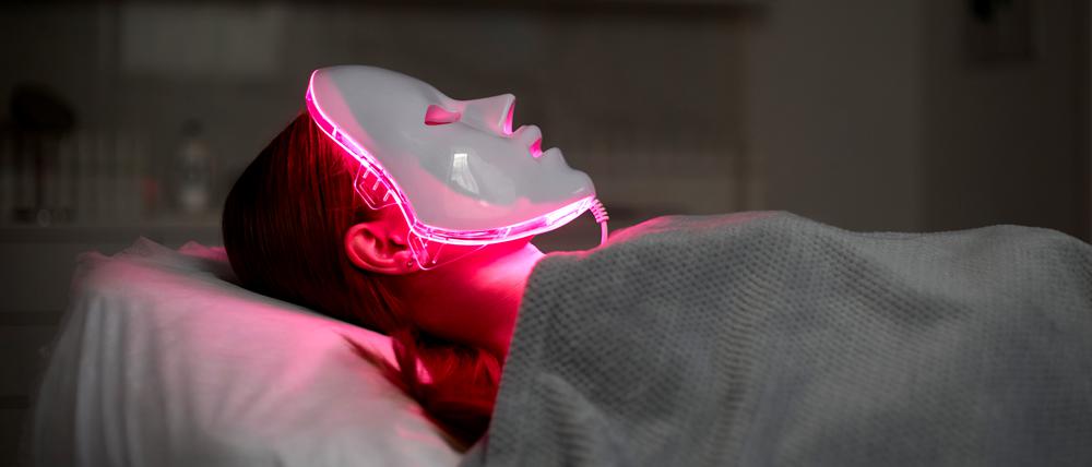 Eine Frau lässt sich mit einer LED-Maske mit rotem Licht behandeln. (Symbolbild)