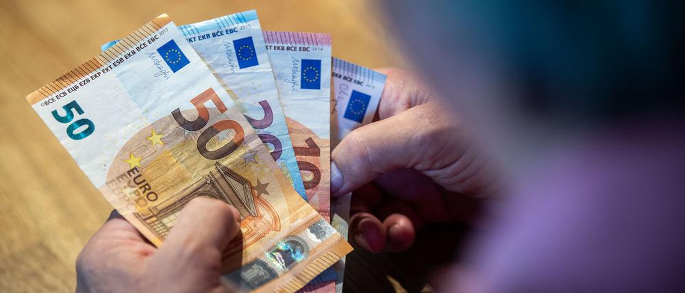 Ein älterer Mann sitzt an einem Tisch und zählt Geld. (Symbolbild)