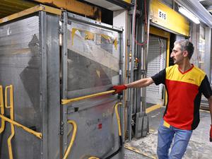Ein Mitarbeiter bei DHL zieht einen Paketwagen.