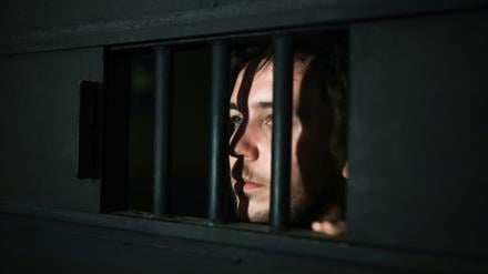 Ein junger Mann blickt aus einer Gefängnistür. Sie gelten als kalt, manipulierend, gefährlich. Doch sind Jugendliche mit psychopathischen Zügen wirklich verloren?