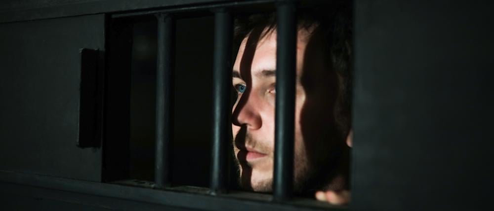 Ein junger Mann blickt aus einer Gefängnistür. Sie gelten als kalt, manipulierend, gefährlich. Doch sind Jugendliche mit psychopathischen Zügen wirklich verloren?