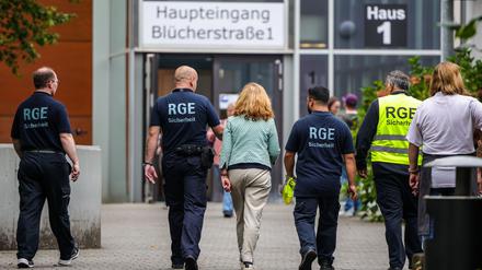 Mehrere Mitarbeiter der Schule und eines Sicherheitsunternehmens gehen auf dem Gelände der Schule, in der ein Angriff auf eine Lehrerin stattgefunden hat. 