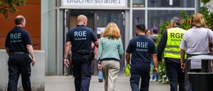 Mehrere Mitarbeiter der Schule und eines Sicherheitsunternehmens gehen auf dem Gelände der Schule, in der ein Angriff auf eine Lehrerin stattgefunden hat.