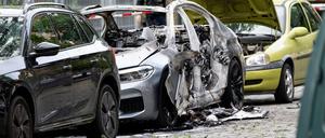 Ein ausgebranntes Auto und weitere zum Teil beschädigte Fahrzeuge stehen an einem Straßenrand. Bei der Explosion eines Sprengsatzes in oder an einem Auto in Berlin-Schöneberg ist ein 22-jähriger Mann schwer verletzt worden.