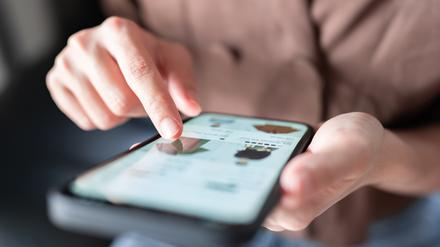 Eine Frau beim Online-Shopping für Modekleidung auf ihrem Smartphone.