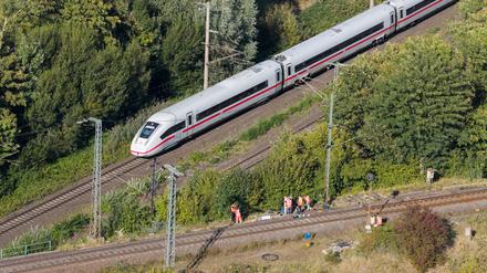 Mitarbeiter der Deutschen Bahn arbeiten nach einem Brand an einer Bahnstrecke in der Nähe eines Stellwerkes, als ein langsam fahrender verspäteter ICE der Deutschen Bahn von Berlin nach Hannover vorbeifährt. 