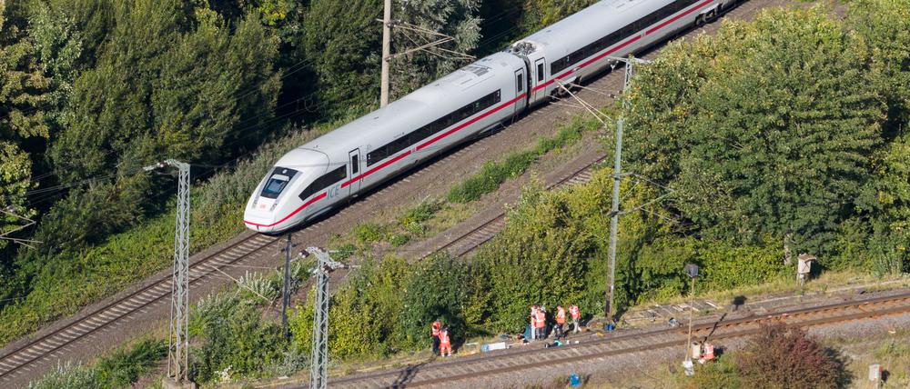 Mitarbeiter der Deutschen Bahn arbeiten nach einem Brand an einer Bahnstrecke in der Nähe eines Stellwerkes, als ein langsam fahrender verspäteter ICE der Deutschen Bahn von Berlin nach Hannover vorbeifährt. 