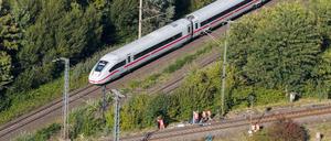 Mitarbeiter der Deutschen Bahn arbeiten nach einem Brand an einer Bahnstrecke in der Nähe eines Stellwerkes, als ein langsam fahrender verspäteter ICE der Deutschen Bahn von Berlin nach Hannover vorbeifährt.