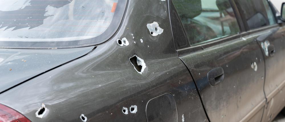 Ein Sedan mit Einschusslöchern von Granatsplittern steht auf einem Parkplatz (Symbolbild).