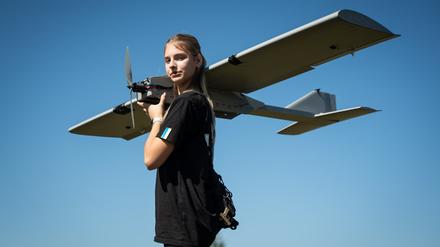 Eine junge Frau hält eine neue ukrainische Kamikaze-Drohne auf den Schultern.