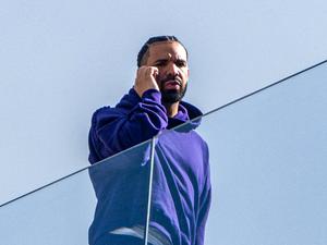 Rapper Drake telefoniert hinter einer Glasfassade. (Archivbild)