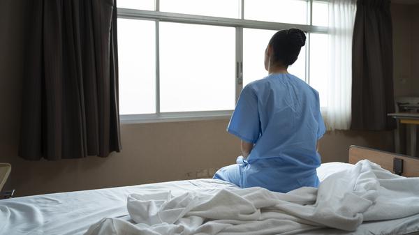 Eine Frau sitzt in einem Krankenhaus auf dem Bett.