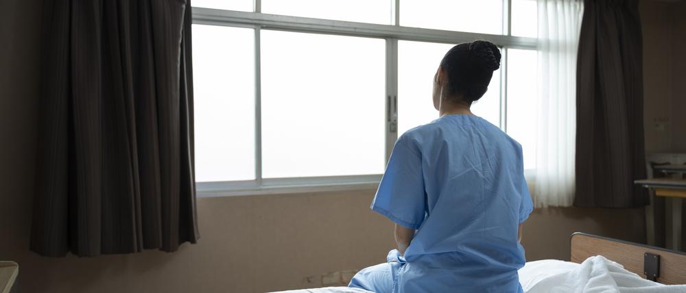 Eine Frau sitzt in einem Krankenhaus auf dem Bett.