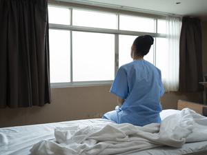Eine Frau sitzt in einem Krankenhaus auf dem Bett.